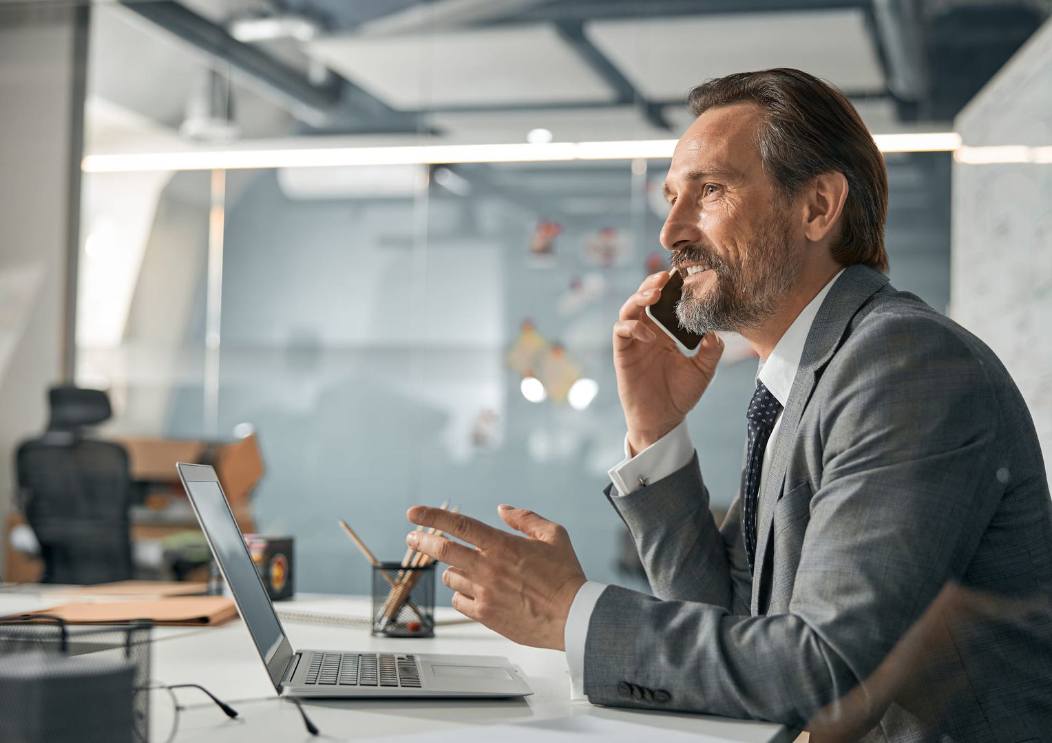 Ein Mann in Anzug und Krawatte spricht am Telefon und wirkt dabei professionell und engagiert
